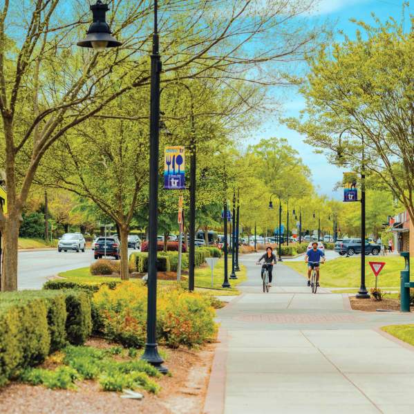 Two bikers cycling along the Prisma Health Swamp Rabbit Trail in downtown Travelers Rest, SC.