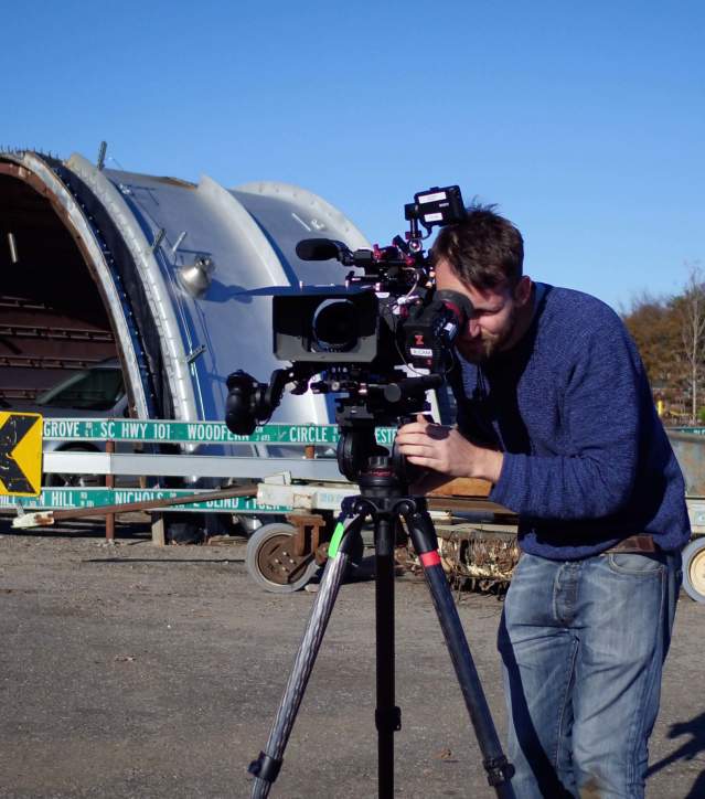 Man filming with camera equipment outdoors at an industrial environment