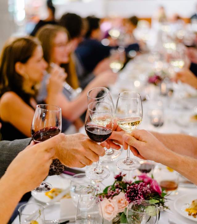 Glasses of wine cheersing over a formally set table