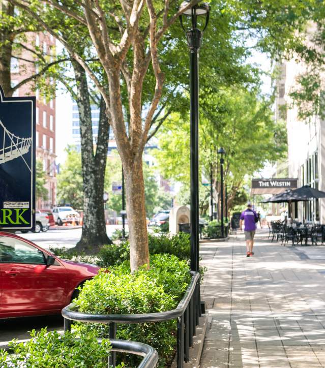 Main street sidewalk with a sign that informs visitors that Falls Park is in 2 blocks.