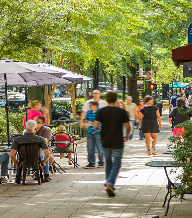Pedestrians walking and diners sitting on Main Street in downtown Greenville, SC.