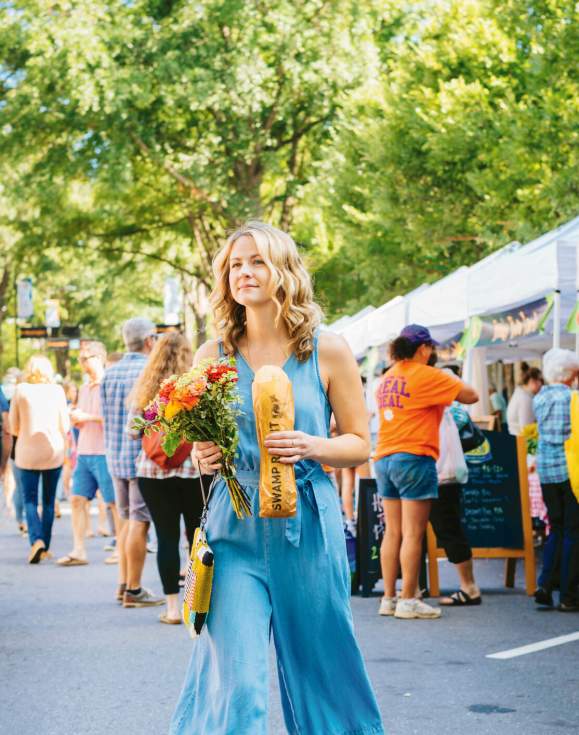 A female shopper walks the length of the TD Saturday Market with Stecca bread and fresh flowers in downtown Greenville, SC.