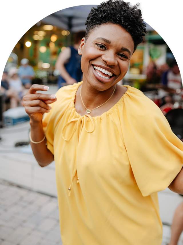 Woman in yellow shirt smiling and snapping her fingers.