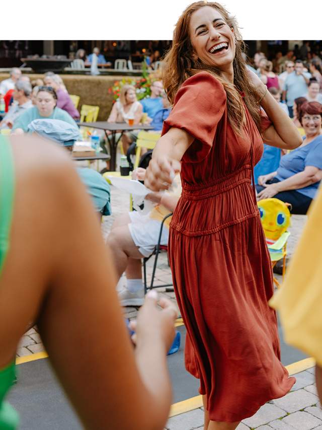 Woman smiling and dancing on a pretty day in Noma Square.