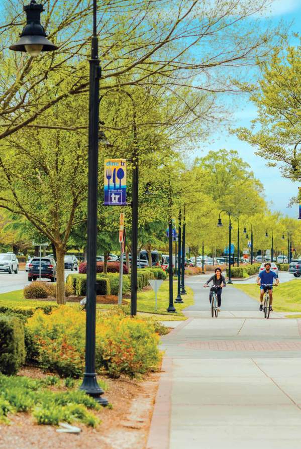 Two bikers cycling along the Prisma Health Swamp Rabbit Trail in downtown Travelers Rest, SC.