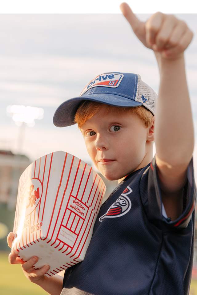 A boy gives a thumb's up with his popcorn at a Greenville Drive baseball game in Greenville, SC.