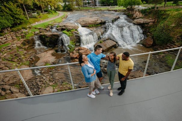 Group of four friends atop the Liberty Bridge & Reedy River Falls