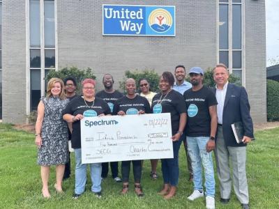 Volunteer group from Infinite Possibilities poses with a generous donation check