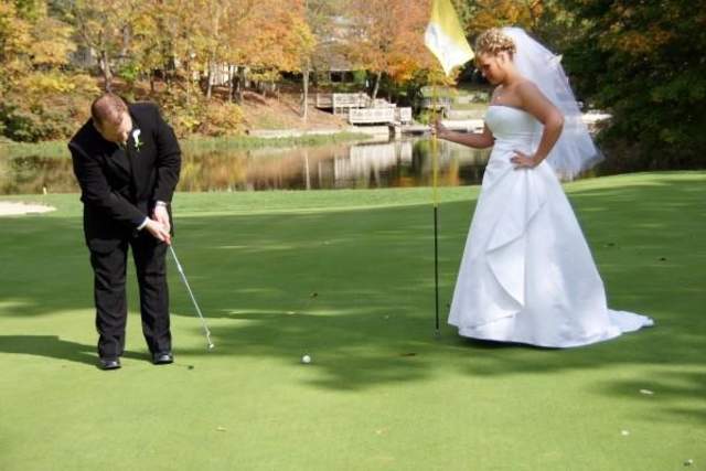 Two people, one in a white wedding dress and the other in a dark suit, standing on a green golf course near a small pond.