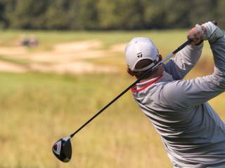 Golfer mid-swing on a golf course.