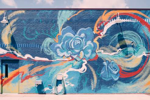A close-up of a colorful mural featuring large blue flowers and red abstract shapes.