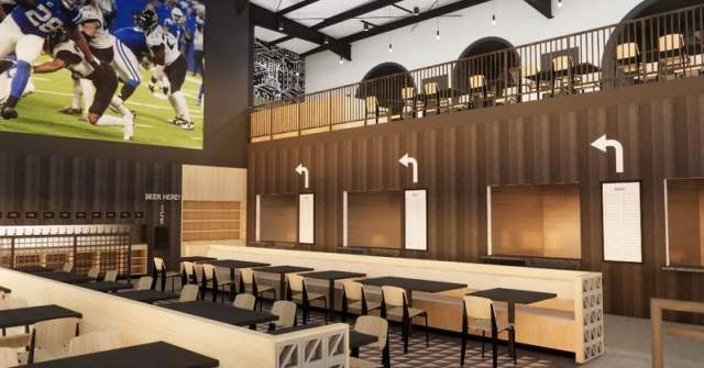 Interior rendering of a modern sports venue dining area with long communal tables, bar seating, and wood-paneled walls, featuring a mezzanine level with additional seating and a large wall-mounted screen displaying a football game.