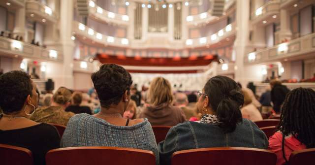 Row of people sitting in spacious Palladium Theater ready for performance to begin