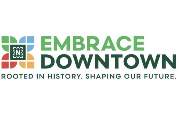 The “Embrace Downtown” logo with the words “Embrace Downtown” in green and blue text. To the left is a square icon made of four colored blocks—green, blue, orange, and red—with a stylized white emblem inside. Below the name is the tagline, “Rooted in history. Shaping our future.”