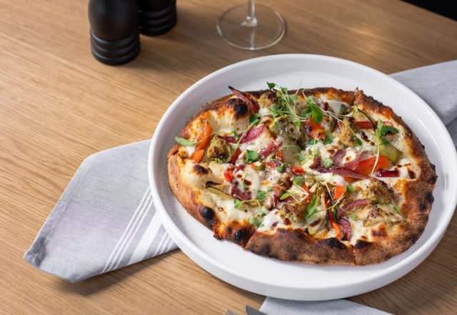 Craft pizza with various toppings on a white plate.