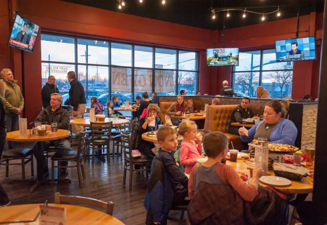 Restaurant interior at Noble Roman's with families enjoying pizza.
