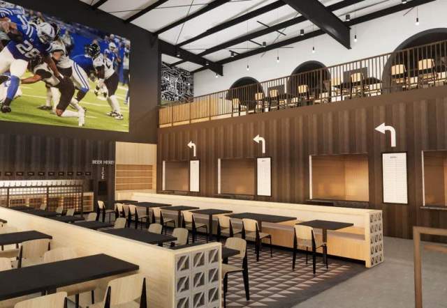 Interior rendering of a modern sports venue dining area with long communal tables, bar seating, and wood-paneled walls, featuring a mezzanine level with additional seating and a large wall-mounted screen displaying a football game.