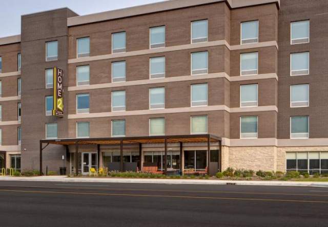 Brick exterior with signage and covered patio of Home2 Suites