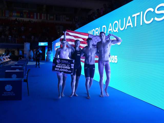 World Aquatics competitors posing on a lit stage with event branding and blue lighting.