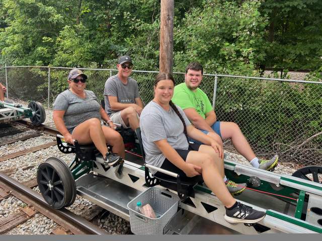 Group of friends sitting on rail bikes near the Nickel Plate Express rail line on a summer day.