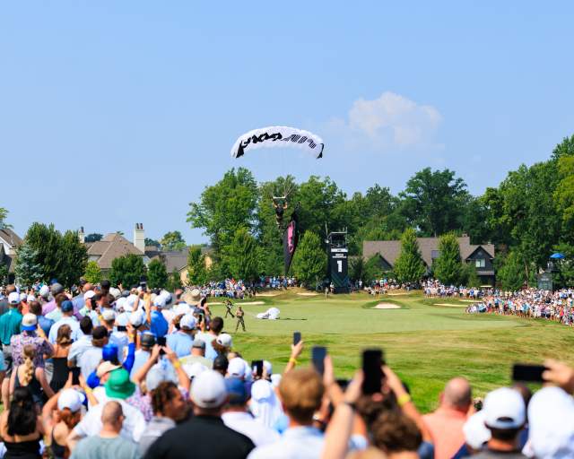 Skydiver with branded LIV Golf parachute landing on the course during pre-event festivities.