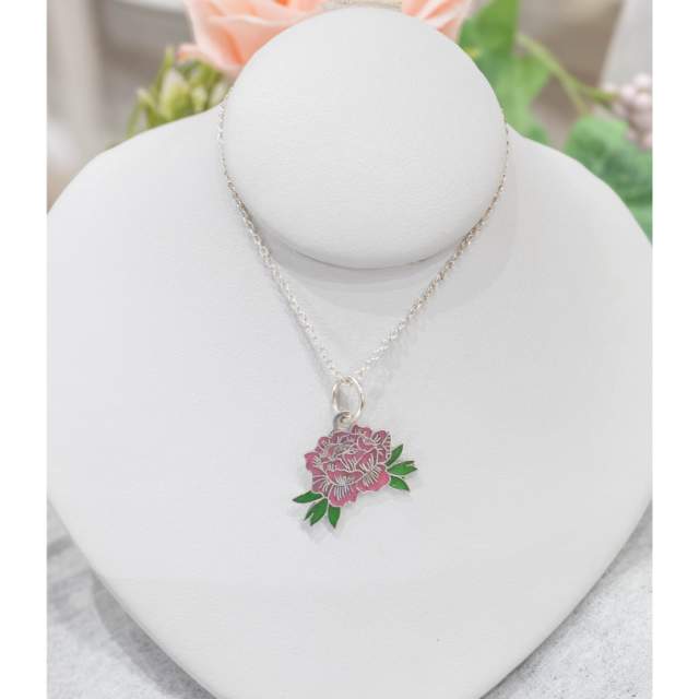“Silver necklace displayed on a white jewelry bust, featuring an enamel peony flower charm in shades of pink with green leaves.