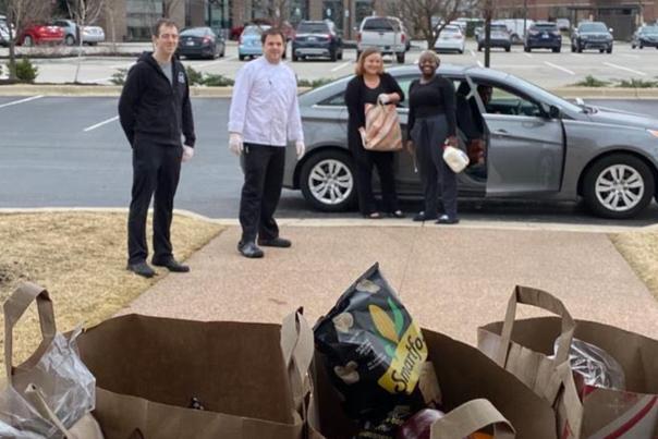 A small group of people standing near a car in a parking area with buildings visible in the background, and a close-up on groceries in bags.