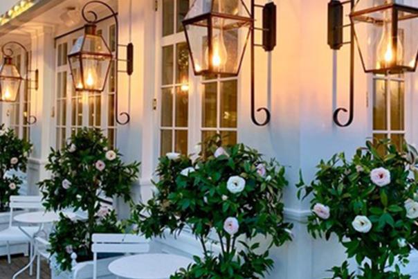 The elegant storefront of "The Cake Bake Shop" featuring white flower arrangements and hanging lanterns.