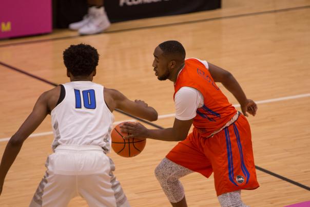 Youth basketball players in action during a Nike EYBL game, with one player defending the ball.