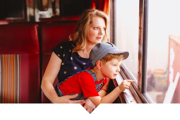 A woman and a young boy sitting inside a train car looking out the window.