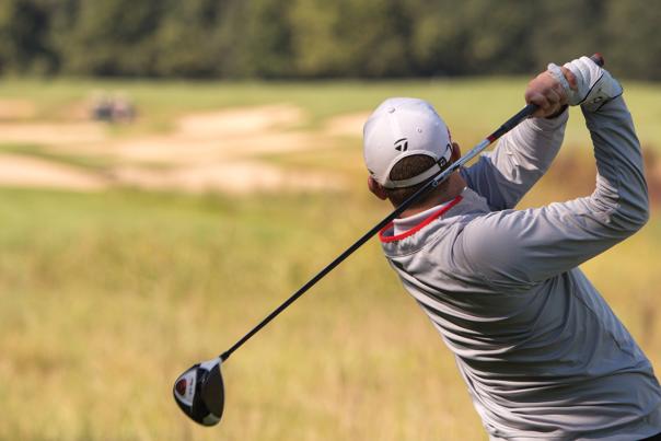 Golfer mid-swing on a golf course.