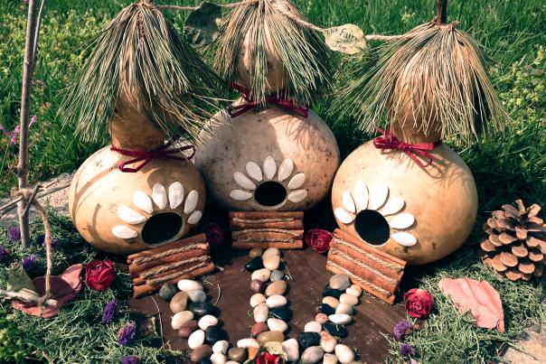 Several decorative birdhouses shaped like pods, decorated with natural materials like pine needles.