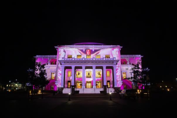 The Palladium building lit up with colorful, dramatic stage lighting at night for Palladiscope.