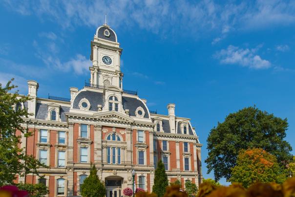 A multi-level historic brick building with a central clock tower under a clear sky.