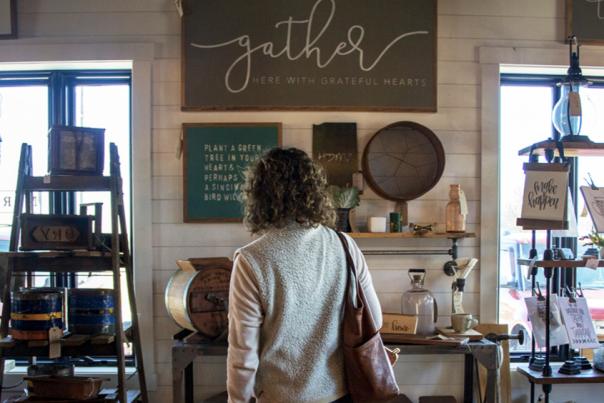 A person standing inside a shop with signage, shelves, and hanging décor.