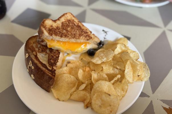 Three-Cheese Grilled Cheese at The Bread Basket Cafe & Bakery, served with chips.