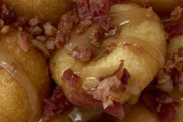 Hometown Mini Donuts

Close-up of golden mini donuts topped with crispy bacon crumbles and drizzled with rich caramel sauce. The warm donuts are piled together on a white plate, highlighting the sweet-and-salty flavor combination and soft, fresh texture.