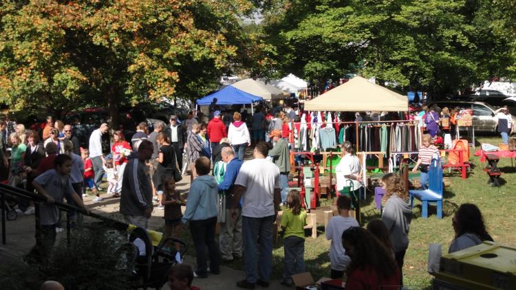 Families and visitors browse craft and community vendor booths under the trees during the Quaker Day Festival in Plainfield, Indiana.