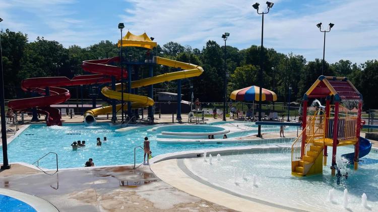 Outdoor aquatic center with colorful waterslides, splash play features and families swimming on a sunny summer day in Hendricks County, Indiana.