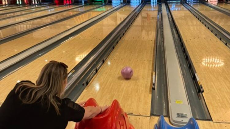 A woman using a wheelchair releases a bowling ball down the lane with an adaptive bowling ramp at Pinheads in Brownsburg.