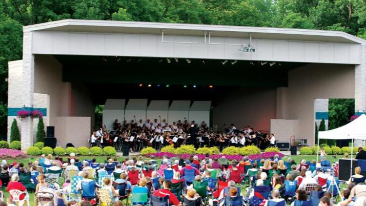 Audience members sit in lawn chairs before the stage in Hummel Park, listening to live music.