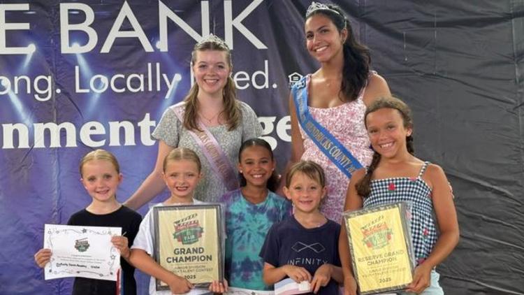 Seven young boys and girls pose with plaques and trophies