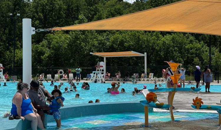 Families enjoy the shallow kiddie pool and splash area at Murphy Aquatic Park in Avon, featuring a gradual entry ledge and shaded seating nearby.