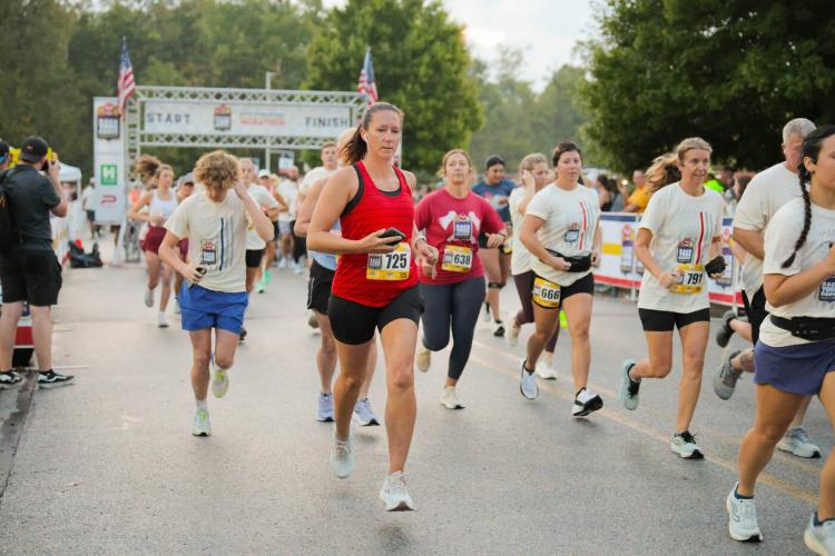 Runners cross the starting line at the Back Your Badge Marathon in Plainfield, Indiana, as participants begin their race through the community.