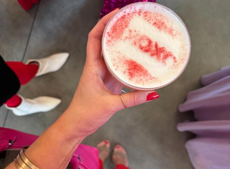 Woman holding a festive Valentine’s-themed drink at a Galentine’s celebration.