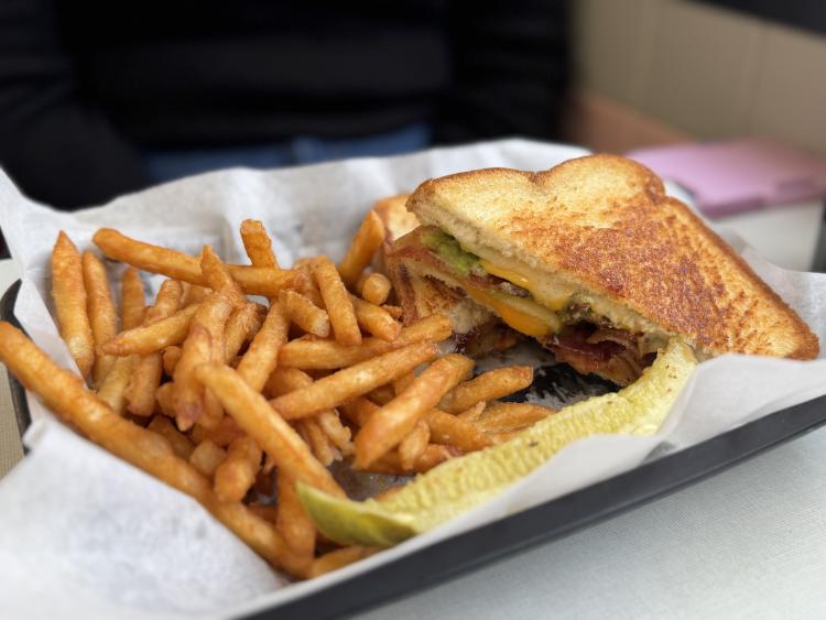 Deluxe Grilled Cheese at Oasis Diner served with french fries and a pickle slice.