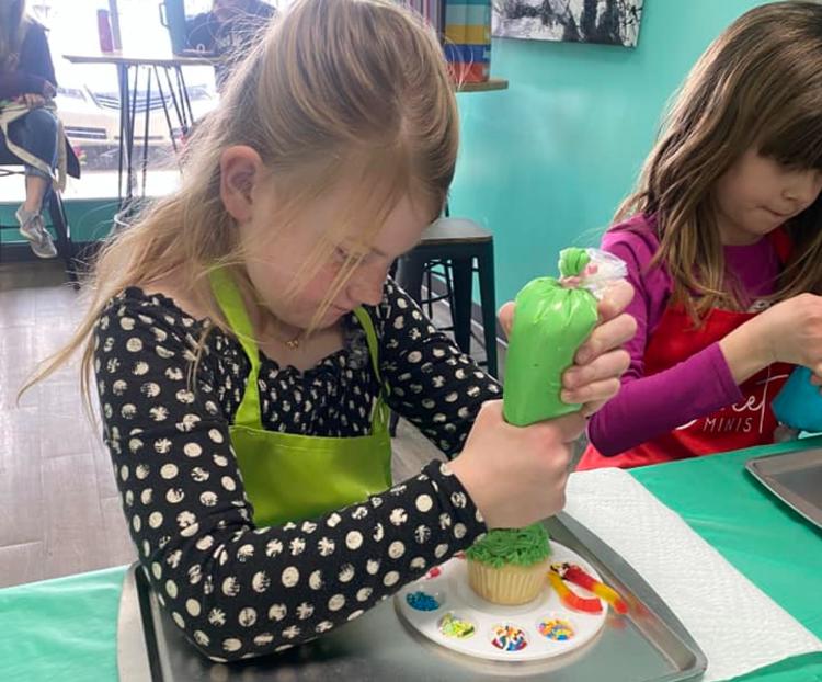 Girl decorating a mini cake at a Sweet Mini's party