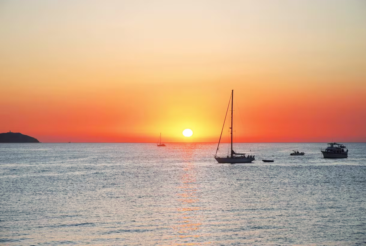 Pôr do sol sobre o mar com veleiros junto à costa de Ibiza