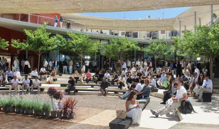 Asistentes participando en un evento profesional MICE en un espacio moderno de Ibiza, reunidos al aire libre en un anfiteatro rodeado de zonas verdes y arquitectura contemporánea, durante una conferencia o presentación.