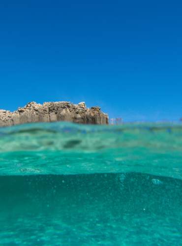 O Mar Mediterrâneo visto de dentro, com as suas águas turquesas e transparentes, sob um céu azul límpido.